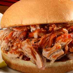 Close-up of a pulled pork sandwich with barbecue sauce on a bun.